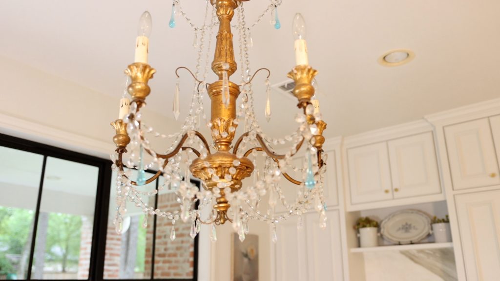 A glam chandelier hangs from Amitha Verma’s kitchen ceiling with gold painted wood and glass crystals.